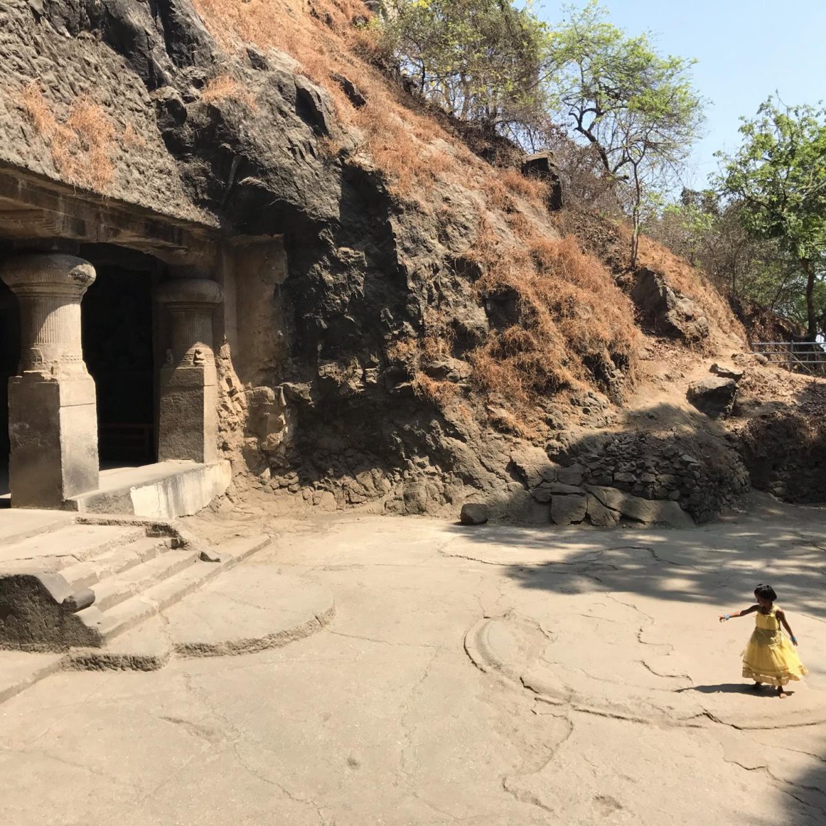 A girl plays at a temple carved out of rock