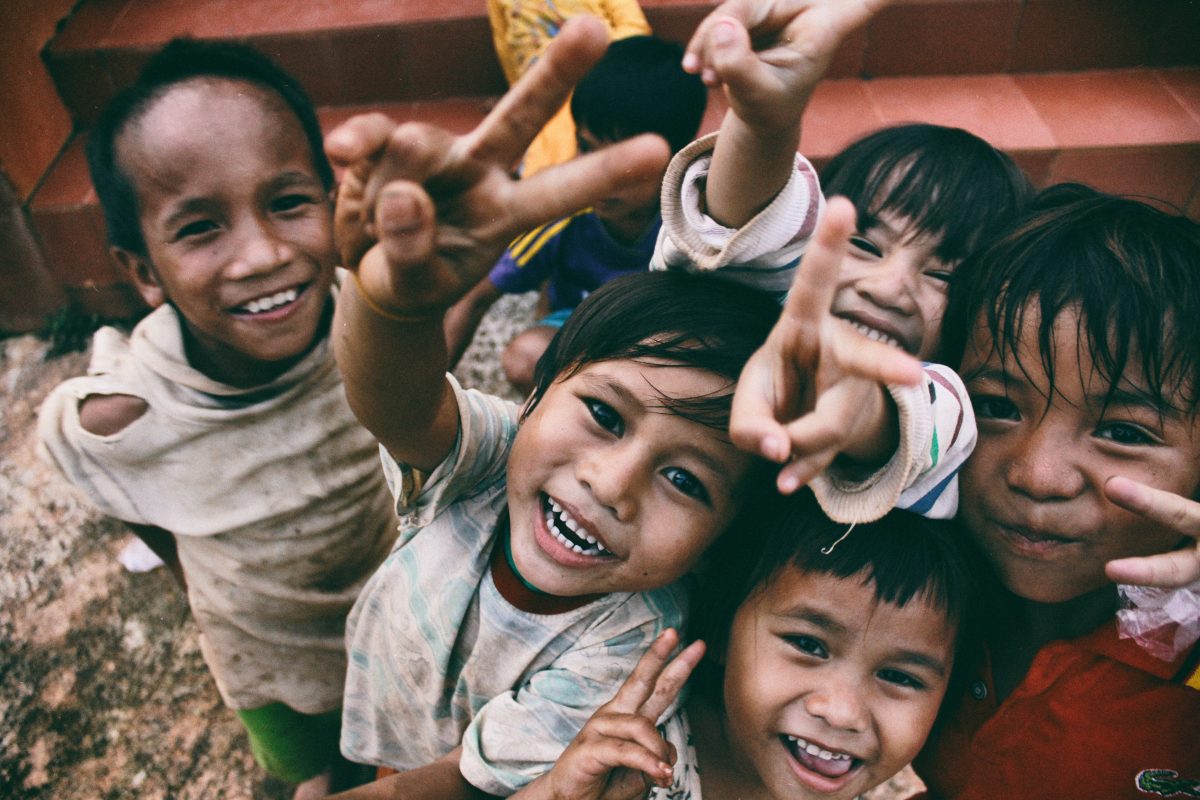 Photo of children smiling and making peace sign.